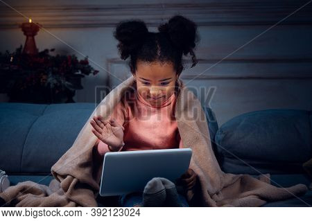 Happy African-american Little Girl During Video Call With Laptop And Home Devices, Looks Delighted A