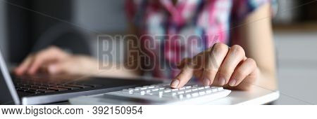 Close-up Of Young Woman Working On Computer And Typing On White Calculator. Female Accounting Family