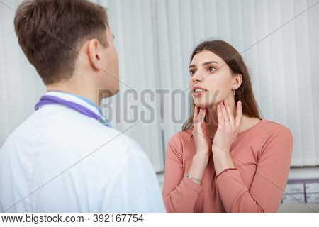 Young Woman With Sore Throat Visiting Doctor. Female Patient With Seasonal Flu On Medical Appointmen