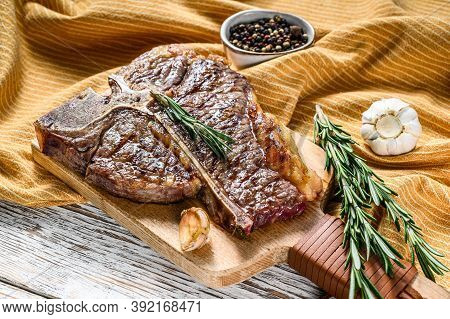 Grilled T Bone Steak On A Chopping Board. Cooked Tbone Beef. White Wooden Background. Top View