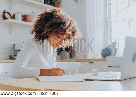 An African-american Young Girl With A Buxom Hairstyle Takes Online Training At Home Sitting In The K