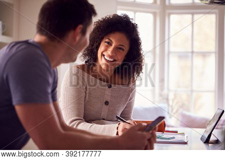 Couple With Digital Tablet Working From Home On Kitchen Counter