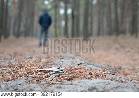 Young Man Loses His Keys Bunch On Russian Autumn Fir Wood Path. Carelessness And Losing Keys Concept