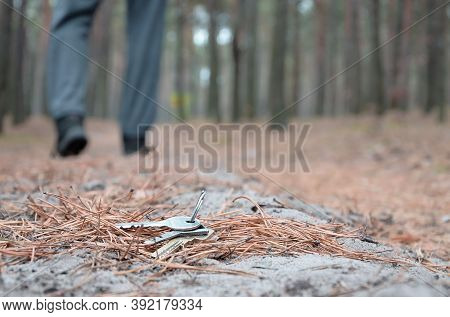 Young Man Loses His Keys Bunch On Russian Autumn Fir Wood Path. Carelessness And Losing Keys Concept