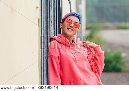 Portrait Of A Young Girl With Short Colorful Hair And Nose Piercing Satanding Near The Wall With Woo