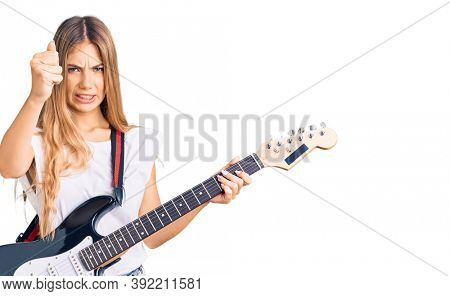 Beautiful caucasian woman with blonde hair playing electric guitar annoyed and frustrated shouting with anger, yelling crazy with anger and hand raised 
