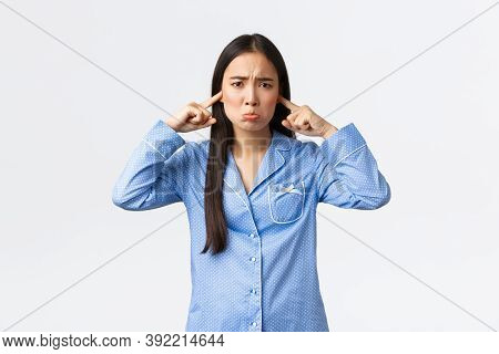 Timid And Sad Asian Girl In Blue Pajamas Pouting And Whining, Shut Ears With Fingers And Sulking Dis