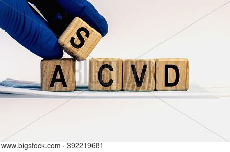 Text Ascvd Made From Wooden Cubes. Hands In A Blue Glove.