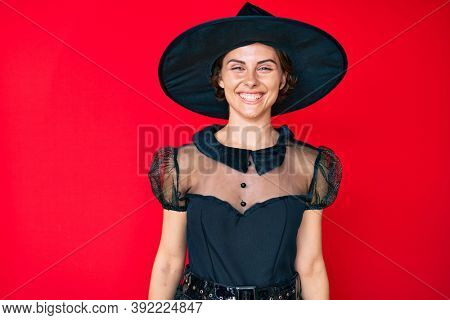 Young hispanic woman wearing witch halloween costume looking positive and happy standing and smiling with a confident smile showing teeth 