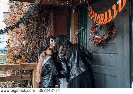 Scary Girls, Sisters, Friends Celebrating Halloween. Playing Treak Or Treat Game On Porch With Garla