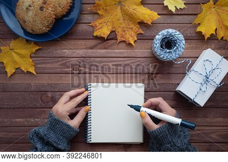 Autumn Falt Lay With Female Hands Keeping Notepad, Brush Pan, Packed Gift, Plate With Cookies And Ye
