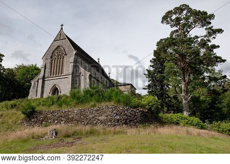 Old Saint Mary & Saint Finnan Catholic Church On A Hill With A Green Tree In Glenfinnan, Scotland, U