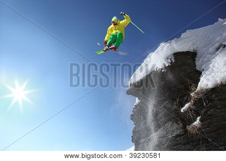 Skier jumping against blue sky from the rock