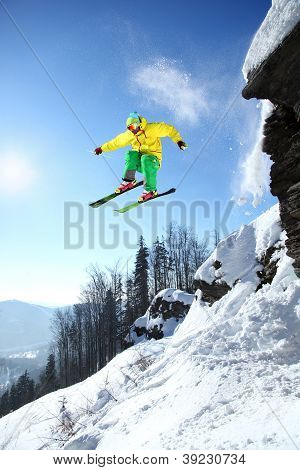 Skier jumping against blue sky from the rock