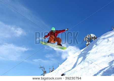 Snowboarder springer mod blå himmel