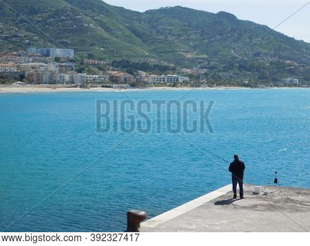 Cefalu, Sicily, Italy. May 10, 2017. A Man Fishing In The Harvor Of Cefalu