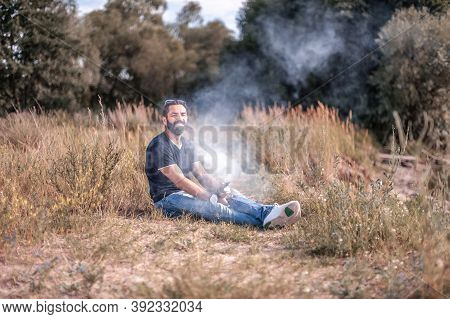 Stylish Vape Man Smoke Electronic Cigarette And Exhals Smoke Cloud. Electronic Cigarette As Alternat