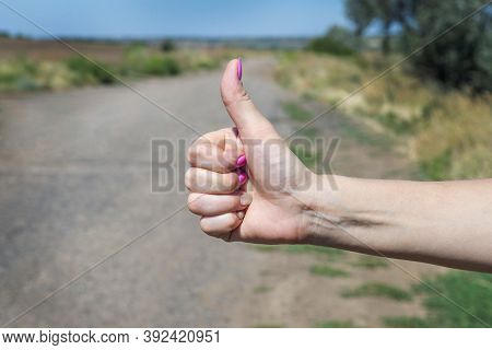 Thumb Up Is The Symbol Or Sign Of Help Or Favor Or Hitchhike From Hitchhiker On A Road. Woman Is Sho