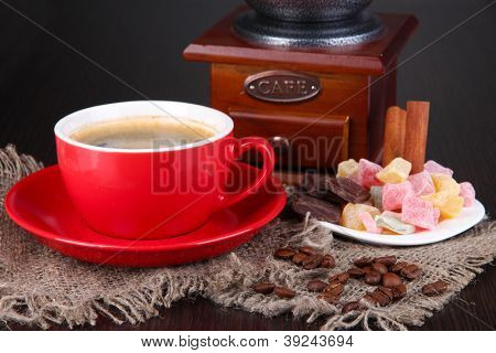 Rote Tasse Kaffee mit Rahat Freude und Kaffeemühle auf Holztisch