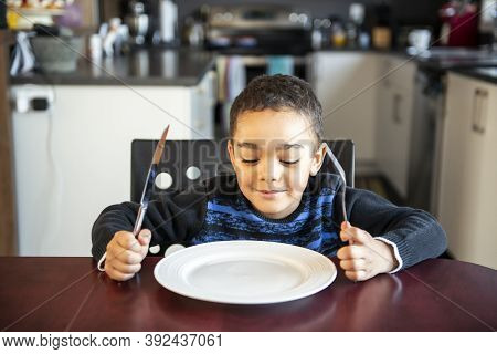 Boy Sitting At The Kitchen Table With Empty Plate