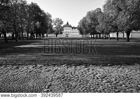Paved Road, Park And Façade Of A Baroque Palace During Autumn In Rogalin, Monochrome
