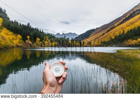 First-person View Of A Female Hand With A Compass On A Background Of A Beautiful Mountain Landscape.