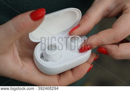 Young Girl Holds White Wireless Firo Vacuum Earbuds. Firo Is Wireless Technologies European Brand