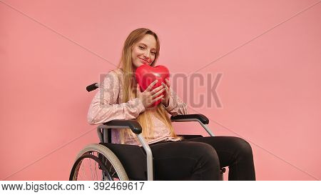 Young Caucaian Disabled Woman In Wheelchair Holding Heart Balloon. High Quality Photo