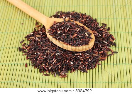 arroz preto com colher de pau, na esteira de bambu