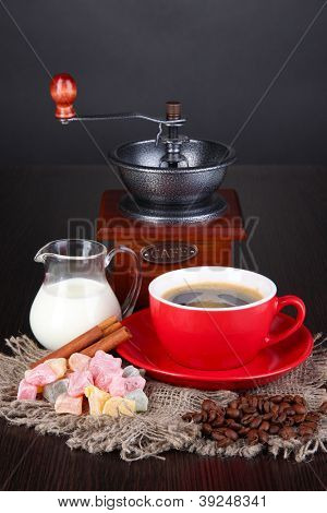 Rote Tasse Kaffee mit Rahat Freude, Milch und Kaffee Mühle auf Holztisch