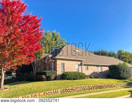 Suburban Corner House With Colorful Autumn Leaves And High Terrain Wall Near Dallas, Texas, Usa
