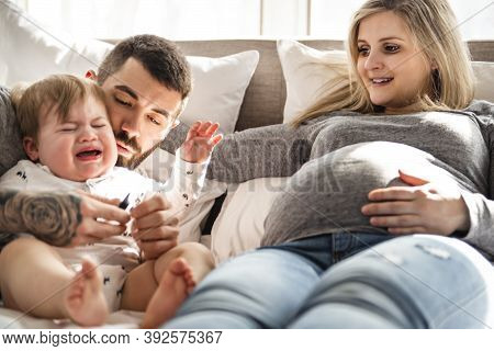 A Crying Son With Parent In Bed At Home