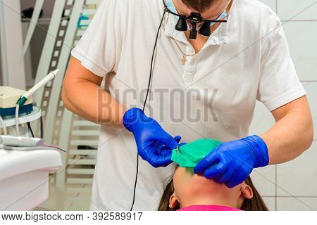 Installation Of A Rubber Dam With A Metal Clamp For Dental Fillings, Sterile And Modern Dental Treat