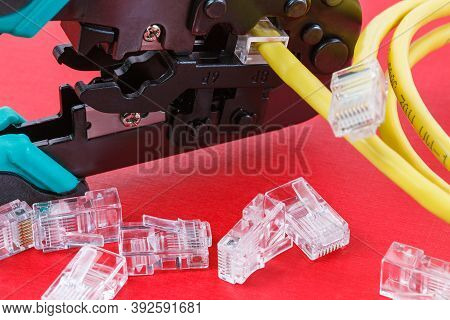 Computer Network Laying Concept. Crimper Tool And Transparent Connectors Connectors On Red Backgroun
