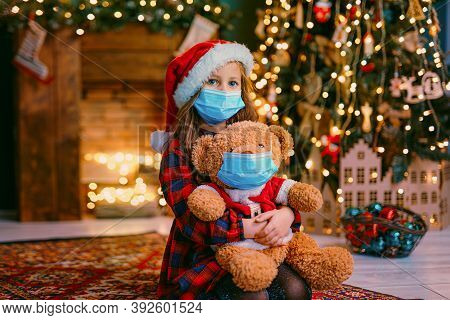 Portrait Of Cutel Little Child Girl In Medical Mask Playing With Taddy Bear, New Year Holiday Concep