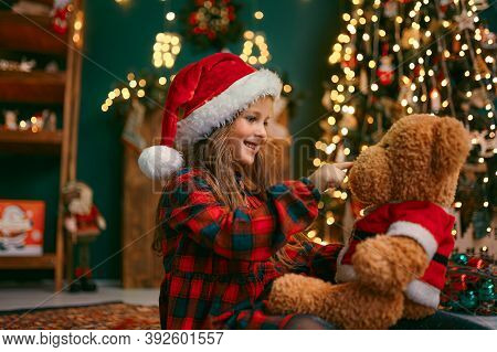 Portrait Of Cutel Little Child Girl In Medical Mask Playing With Taddy Bear, New Year Holiday Concep