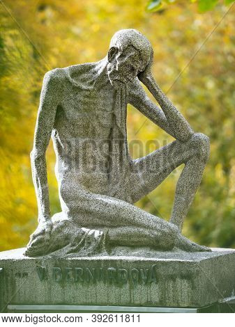 Statue Of Sad Sittingsinewy Man Sit On Family Tombstone.  24th Of October 2020. Hronov, Czechia.  Au