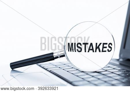 A Magnifying Glass With The Word Mistakes, Magnifier On Laptop Keyboard.
