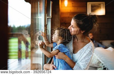 Small Girl With Parents In Wooden Cabin, Holiday In Nature Concept.