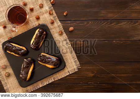 Eclairs With Black Chocolate And White Chocolate With Custard In Plate On Wooden Table. Traditional 