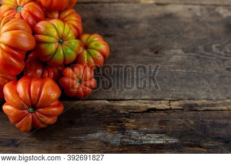 Red Ribbed Tomatoes On A Wooden Background. American Or Florentine Variety Nina. Food On The Table T