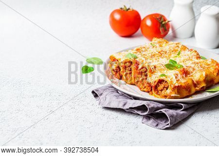 Portion Of Cannelloni With Meat, Tomato Sauce And Cheese On A Gray Plate, Gray Background. Italian C