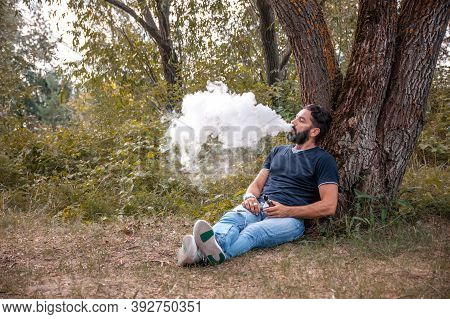 Stylish Brutal Man Smoking An Electronic Cigarette. Man Really Likes Process Of Smoking.