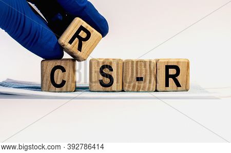 Text Crs-r Made From Wooden Cubes. Hands In A Blue Glove.