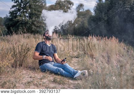 Handsome Vaper Exhales Cloud Of Smoke. Vaping Concept.