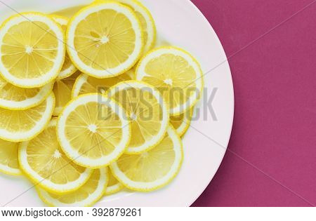 Flat Lay Of Lemon Slices Arranged On White Plate On Purplish-red Surface