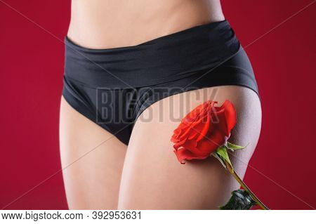 Close-up Of The Thigh And Underbelly Of The Women On The Red Background Next To The Flower Rose Red.