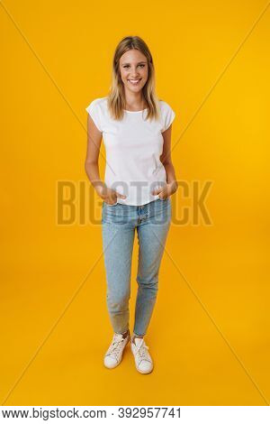 Cheerful beautiful girl smiling while posing at camera isolated over yellow background