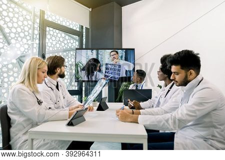 Front View Of Five Multiracial Confident Doctors Discussing Treatment Plan Of Patient While Having V