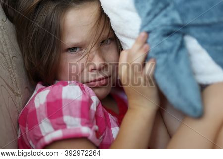 Little Girl Sits On Sofa Offended With Soft Toy. Childrens Whims And Grievances Concept